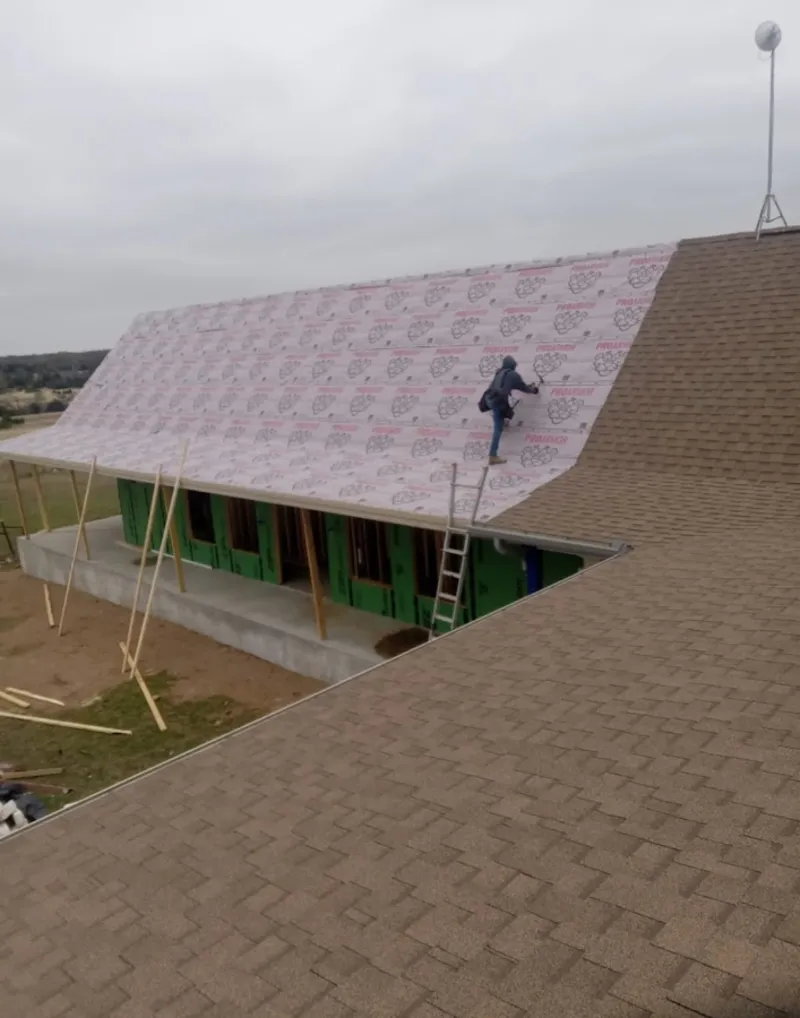 Worker preparing underlayment for a metal roof installation in Waianae